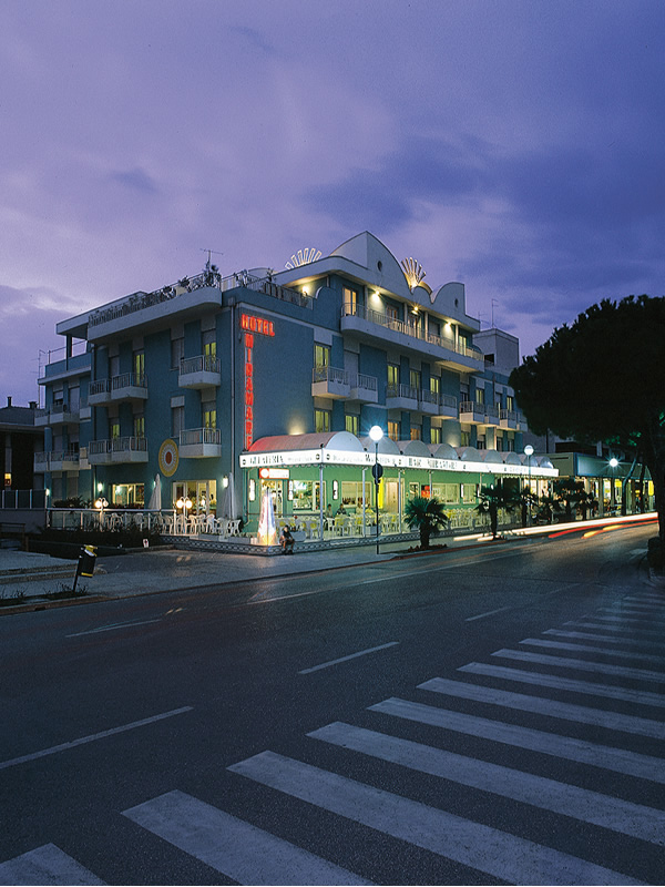 Hotel moderno illuminato di sera, con terrazza esterna.